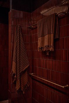 two brown towels hanging on the side of a wooden wall