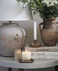 a table topped with two vases filled with flowers and candles next to each other