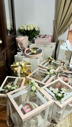 a table topped with lots of boxes filled with cakes and flowers on top of a wooden floor