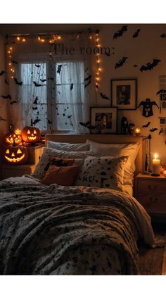 a bedroom decorated for halloween with pumpkins and bats on the wall, lights strung from the window