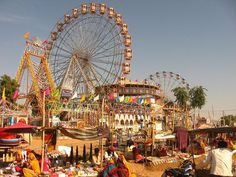 an amusement park filled with lots of rides and people sitting on the ground next to them