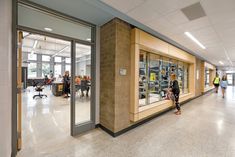 people are walking in and out of an office building with glass doors on both sides