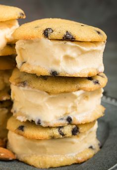 a stack of cookies with ice cream and almonds on a glass plate next to some nuts