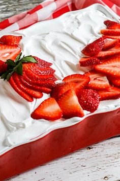 strawberries on top of whipped cream in a red and white dish sitting on a wooden table