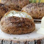 some bread and cheese are sitting on a wooden board next to a slice of butter