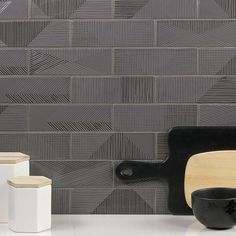 a black and white kitchen counter top next to a wooden cutting board with chopping utensils on it