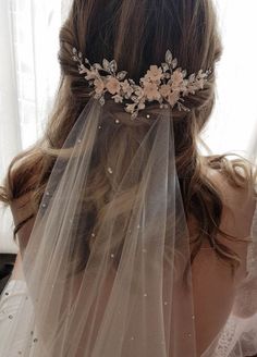 the back of a bride's head wearing a wedding veil with flowers on it