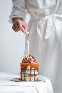 a person lighting a candle on top of a cake