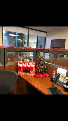 an office cubicle decorated for christmas with presents on the desk, and a phone