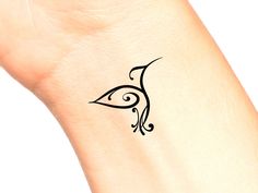 a small black bird tattoo on the ankle is shown in close up, it appears to be an elegant design