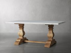 a white marble top dining table with wooden legs and two small posts at the base