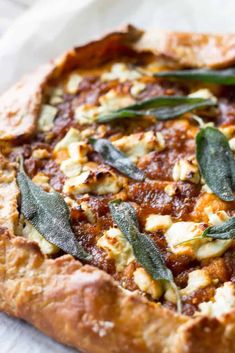 a pizza topped with cheese and sage leaves