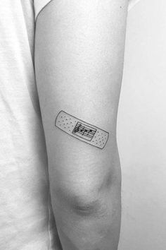 a black and white photo of a person with a band aid tattoo on their arm