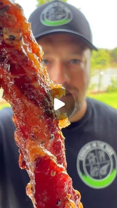 a man holding up a piece of bacon on a stick with ketchup and mustard