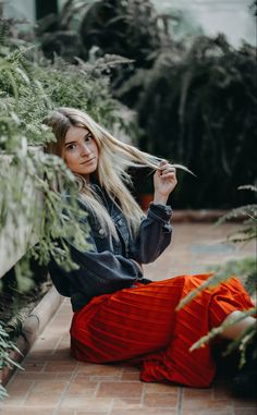 a woman is sitting on the ground with her hair blowing in the wind and looking at the camera