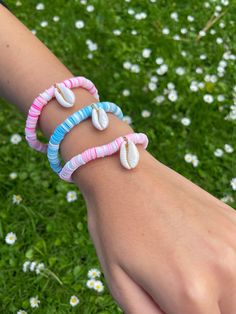 a person is wearing three bracelets with seashells on them in the grass