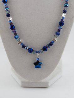 Be a star wherever you go with this starry blue necklace! A blue star gem hangs from a string of beads including silver stars and other sparkly beads of blue, silver and clear. This necklace is 20" long with a lobster clasp closure, strung on flexible beading wire attached to chain. Blue Star-shaped Beaded Necklace, Handmade Blue Star-shaped Beaded Necklaces, Handmade Blue Star Beaded Necklaces, Handmade Blue Beaded Star Necklaces, Blue Star-shaped Adjustable Necklace, Blue Adjustable Star-shaped Beaded Necklaces, Adjustable Blue Star-shaped Beaded Necklace, Adjustable Blue Beaded Star Necklaces, Blue Star Charm Jewelry