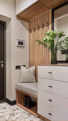 a vase with flowers sitting on top of a wooden bench next to a white dresser