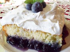 a piece of cake with white frosting and blueberries on top