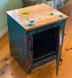 an old wooden box with flowers painted on the inside and sides, sitting on a hard wood floor