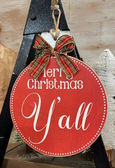 a wooden sign that says merry christmas y'all hanging from a tree with a bow on it