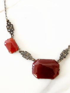 This antique 1920's art deco necklace is wonderful. The necklace features a deep burgundy red rectangle carnelian pendant at the center of the necklace with two additional smaller rectangle stones - one on each side of the center pendant. The carnelian stones are prong set along the silver chain that features marcasite elements throughout, engraving at the back, and a c-clasp closure. A rare and unique piece. ✂-------- M E A S U R E M E N T S -------- Measurements: Chain length: 15 inches width: 1 1/4 inches, length: 1 inch tag/label - brand marker: n/a material(s): carnelian, marcasite, and silver chain condition: excellent antique condition. There is very slight wear. ★ We encourage customers to ask questions and get additional photos of each item before purchase. We do our best to notif Art Deco Red Rectangular Jewelry, Red Rectangular Art Deco Jewelry, Red Rectangle, Carnelian Pendant, 1920s Art, Carnelian Stone, Art Deco Necklace, 1920s Art Deco, Deep Burgundy