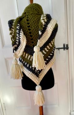 a crocheted shawl with tassels hanging on a mannequin