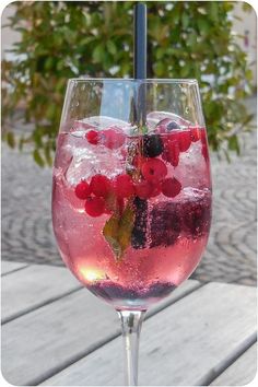 a glass filled with ice and berries on top of a wooden table