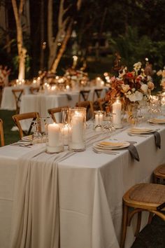 an outdoor dinner table with candles and flowers