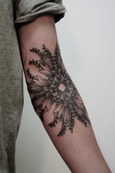 a person with a tattoo on their arm that has flowers and leaves in the middle