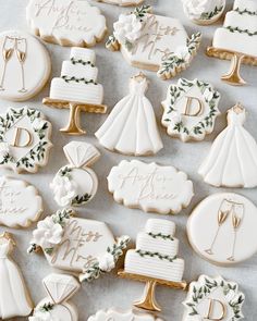 wedding cookies decorated with royal icing and greenery are arranged on a white table