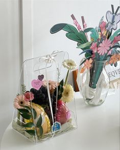 two vases filled with flowers on top of a white table next to each other