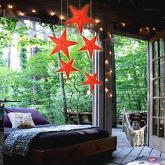 an outdoor bedroom with red stars hanging from the ceiling and lights on the outside wall