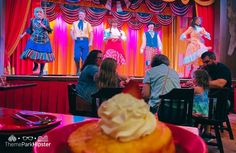 people are sitting at tables in front of a stage with clowns on it and an ice cream sundae