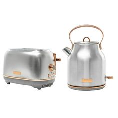 a silver and gold tea kettle sitting next to a toaster on a white background