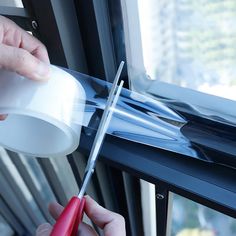 a person is using scissors to cut something out of the side of a window sill