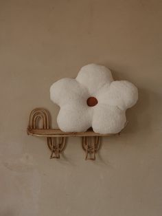 a white flower is hanging on the wall next to two hooks and a coat rack