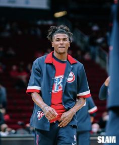 a basketball player standing on the court with his hands in his pockets and looking off to the side