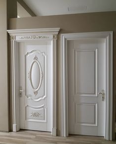 two white doors in an empty room with wood flooring and beige walls on either side