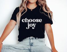 "This Choose Joy T-Shirt is everything you've dreamed of and more. It features a Retro style, bold font with a positive saying. It's sure to be an inspirational shirt that motivates kindness and good vibes! It feels soft and lightweight, with the right amount of stretch. It's comfortable and flattering for both men and women.  H O W - T O - O R D E R  - Be sure to review the size chart in the photos before making your selection. - Select the size and color you want from the drop-down menus. - Click the \"Add to Cart\" button, then proceed to check out once you have added all of your items. M A T E R I A L S Solid Colors are 100% Ring-Spun Cotton, Heather Colors are a Cotton Poly Blend. S H I R T - S I Z I N G All shirts are UNISEX sizing. Please use the Size Chart included in the listing p Inspirational Black Pre-shrunk Top, Inspirational Slogan Shirt, Inspirational Black Relaxed Fit T-shirt, Inspirational Crew Neck Top With Funny Text, Inspirational Crew Neck Top With Quote Print, Inspirational Black Tops With Text Print, Inspirational Short Sleeve Tops With Funny Text, Inspirational Quote Print Crew Neck Top, Inspirational Text Print Black Tops