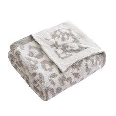 a white and grey blanket with an elephant design on the bottom, in front of a white background