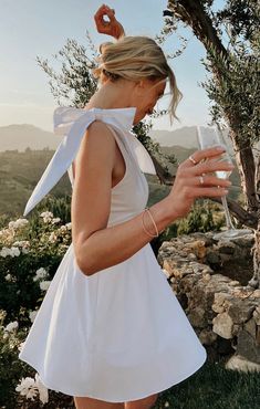 a woman in a white dress holding a wine glass