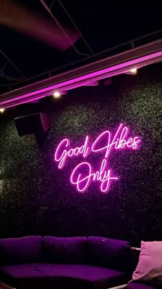 a purple couch sitting in front of a neon sign that says good vibes only