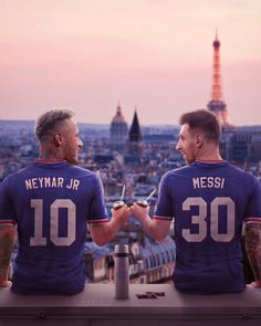 two men sitting on top of a roof looking at each other with the eiffel tower in the background