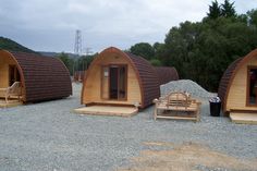 three wooden cabins sitting on top of a gravel field