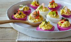 deviled eggs with colorful toppings are arranged on a tray, ready to be eaten