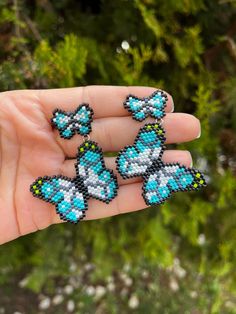 a hand holding three beaded earrings in it's palm