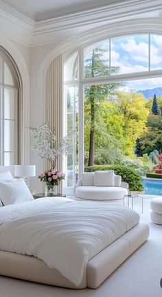 a large white bed sitting in a bedroom next to a window filled with lots of windows