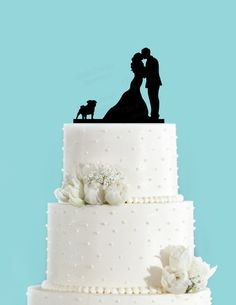 a wedding cake with the silhouettes of two people and a dog on top