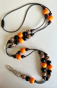 an orange and black beaded necklace on a white table next to a keychain